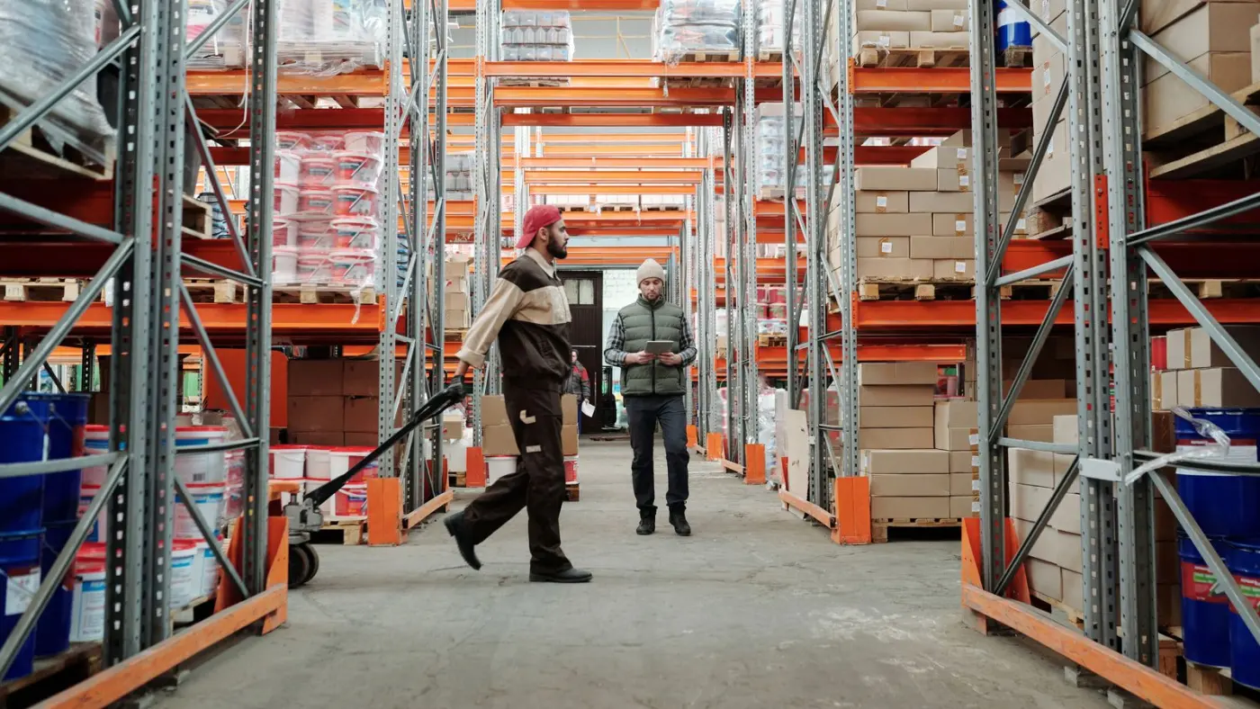Two warehouse staff working through inventory in a storage aisle